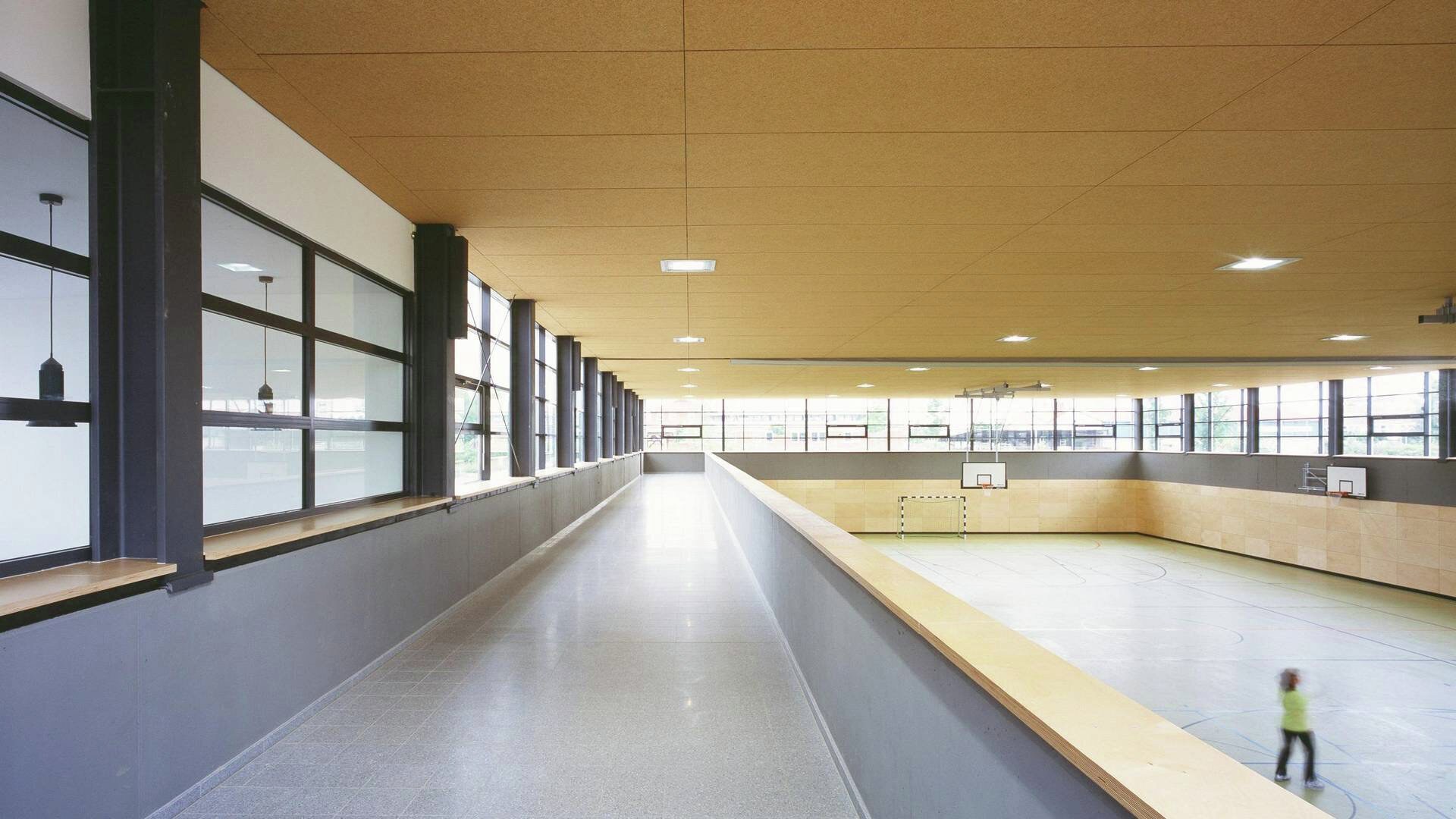 Sporthalle der Berufsschule Waren: Galerie mit Fensterband entlang der Halle unter der hellen Holzdecke